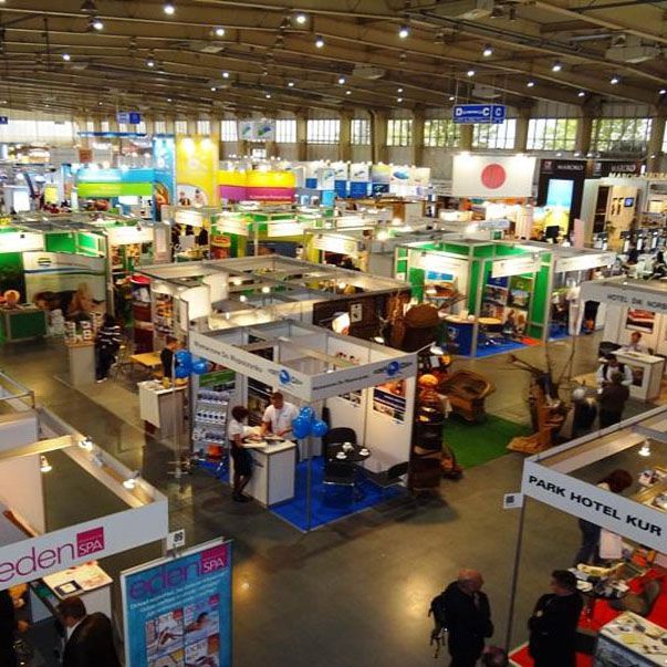 A busy expo hall seen from above, with rows of exhibitor stalls and visitors