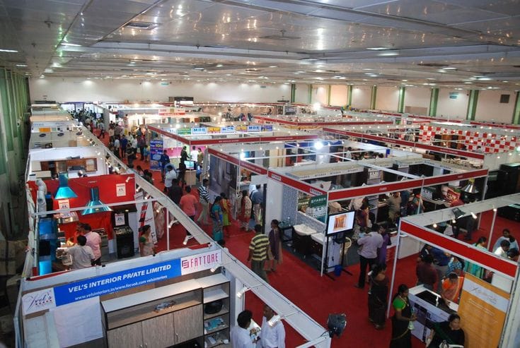 Rows of exhibitor stalls and visitors on a red-carpeted expo floor