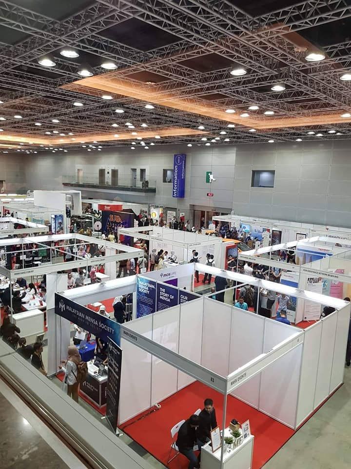 An expo hall seen from above, lined with white shell-scheme stalls